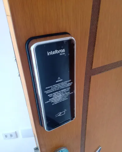 Fechadura digital Intelbras instalada em porta de madeira, outro ângulo